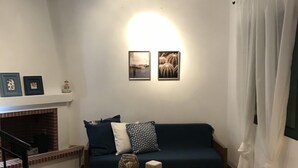 A living room with a fireplace, a blue sofa, a coffee table, and a black bean bag. - Stunning sea-front maisonette (Kassandra)
