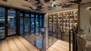 A modern library interior with glass railings, wooden flooring, and bookshelves. - HOTEL Cargo Shinsaibashi (Osaka)