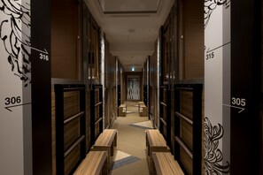 A hotel hallway with numbered rooms, wooden benches, and a patterned carpet. - HOTEL Cargo Shinsaibashi (Osaka)