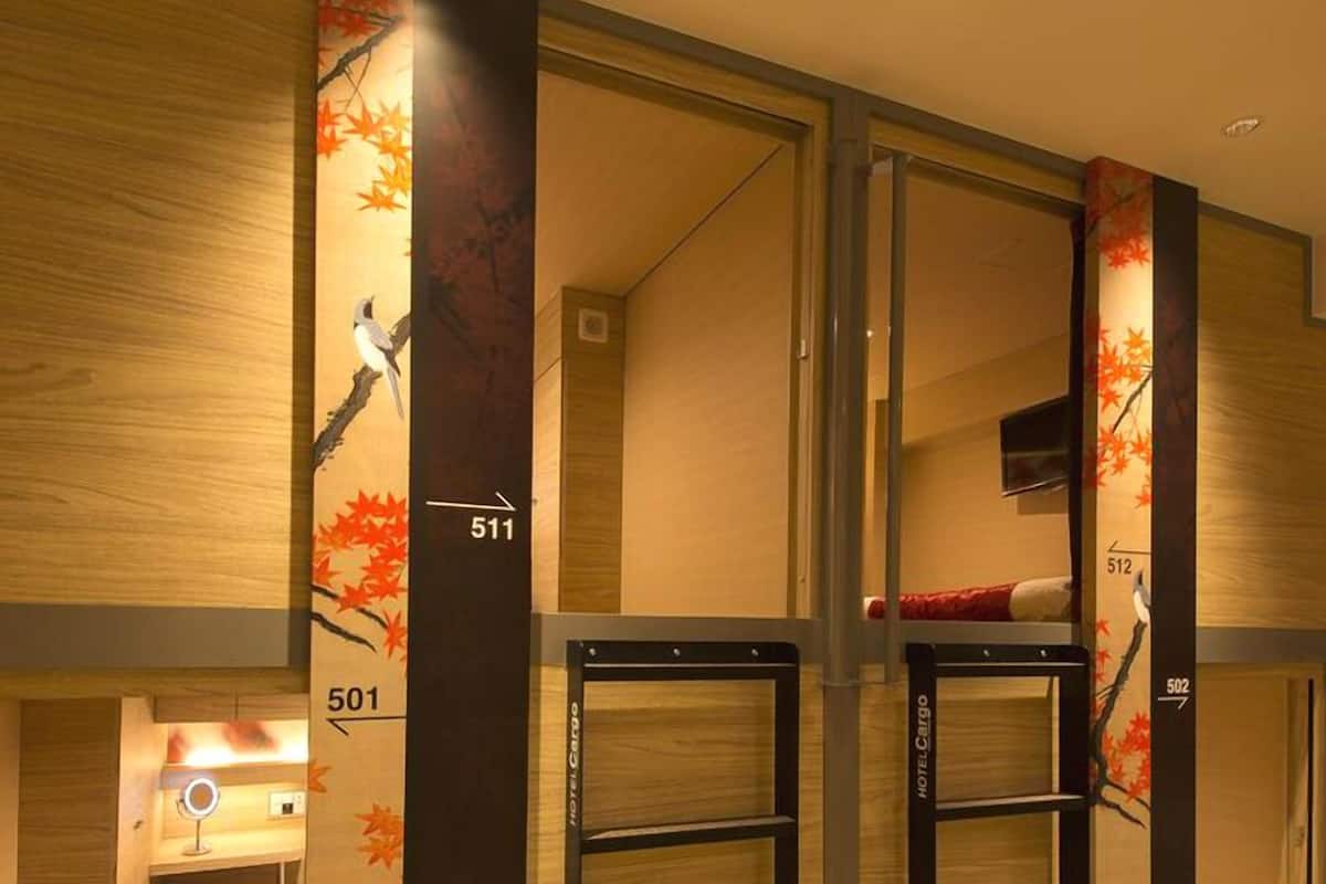 A hotel room with a bunk bed, a small desk with a mirror, and a wall with numbers indicating room positions.