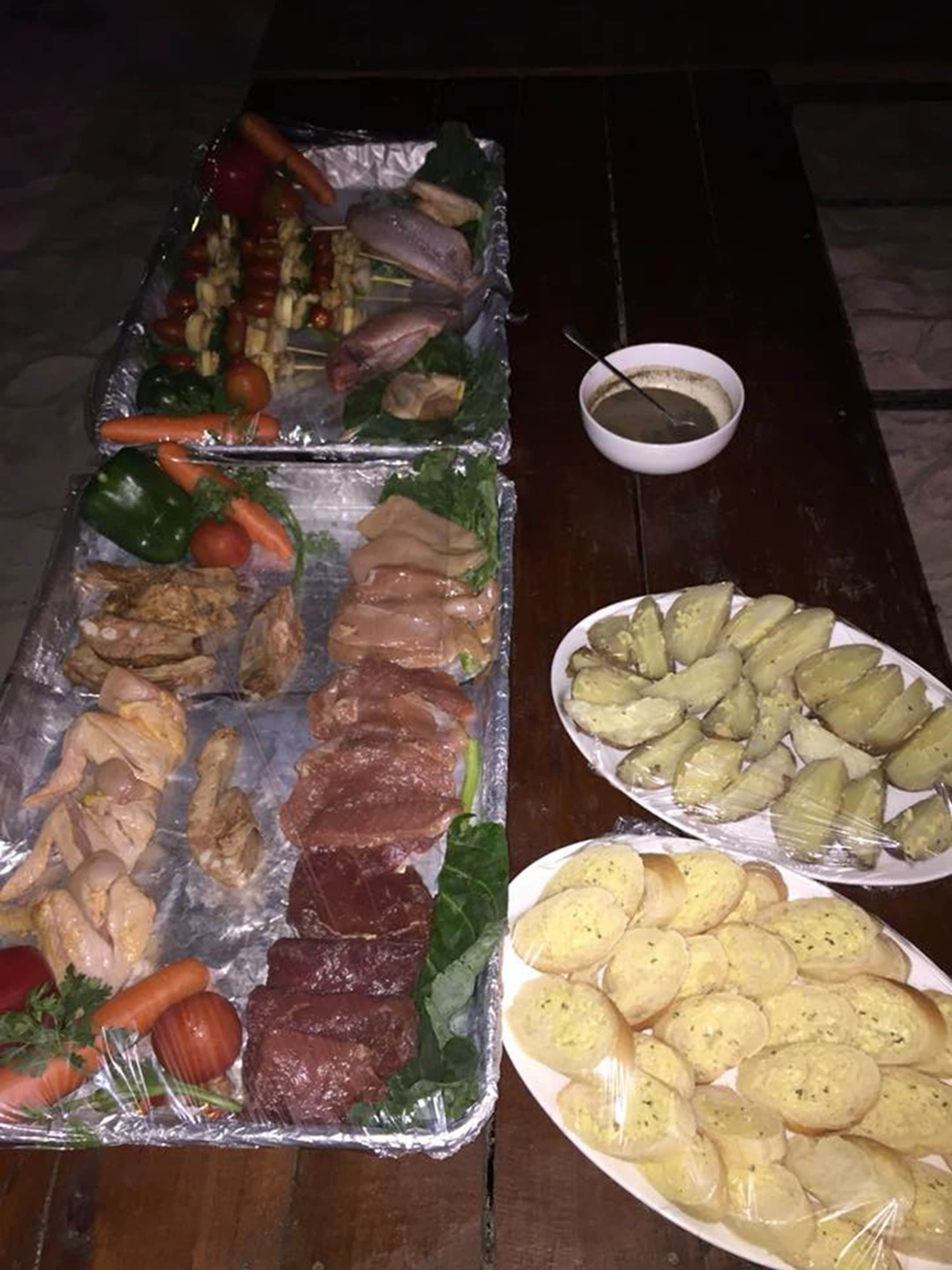 Uma mesa com diversos alimentos, incluindo carnes, legumes e pão.