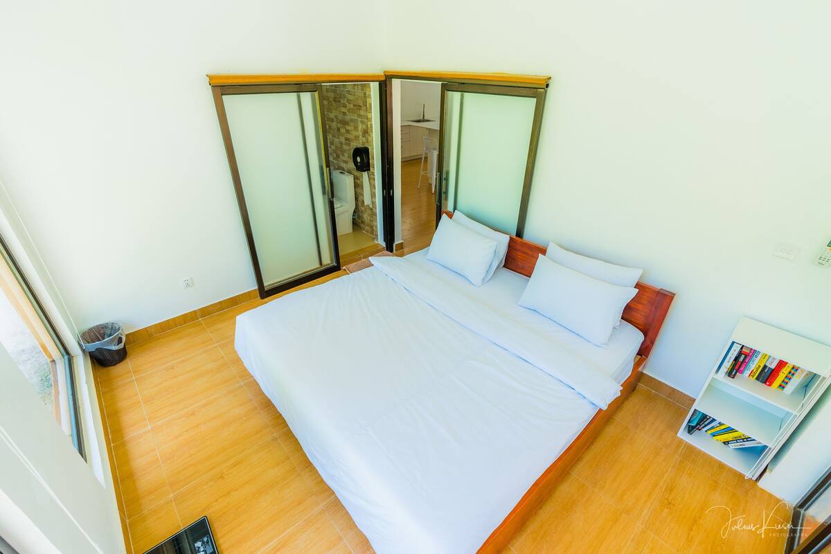 A room with a bed, a bookshelf, and a sliding door leading to a bathroom.