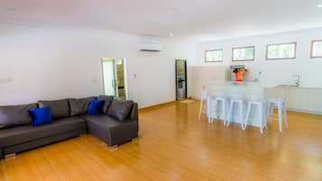 A modern living room with a grey sectional sofa and a dining area with white chairs.