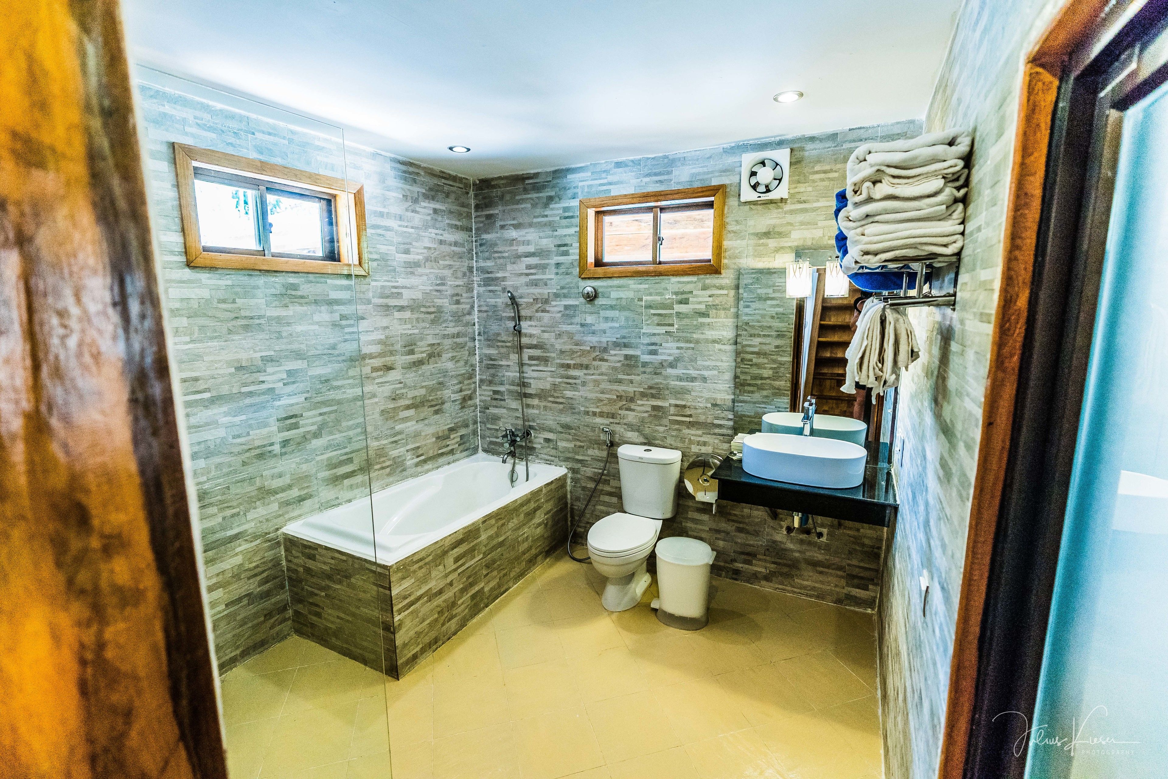 A bathroom with a bathtub, toilet, sink, and a window.