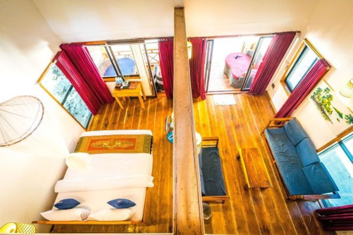 Una habitación compacta con piso de madera, cama, sofá y una pequeña mesa.