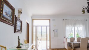 Een eethoek met een tafel met glazen blad, stoelen en uitzicht door een deur naar een buitenbalkon.