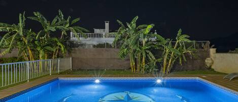 Una piscina con un diseño en forma de estrella en el centro, rodeada de palmeras y una valla.