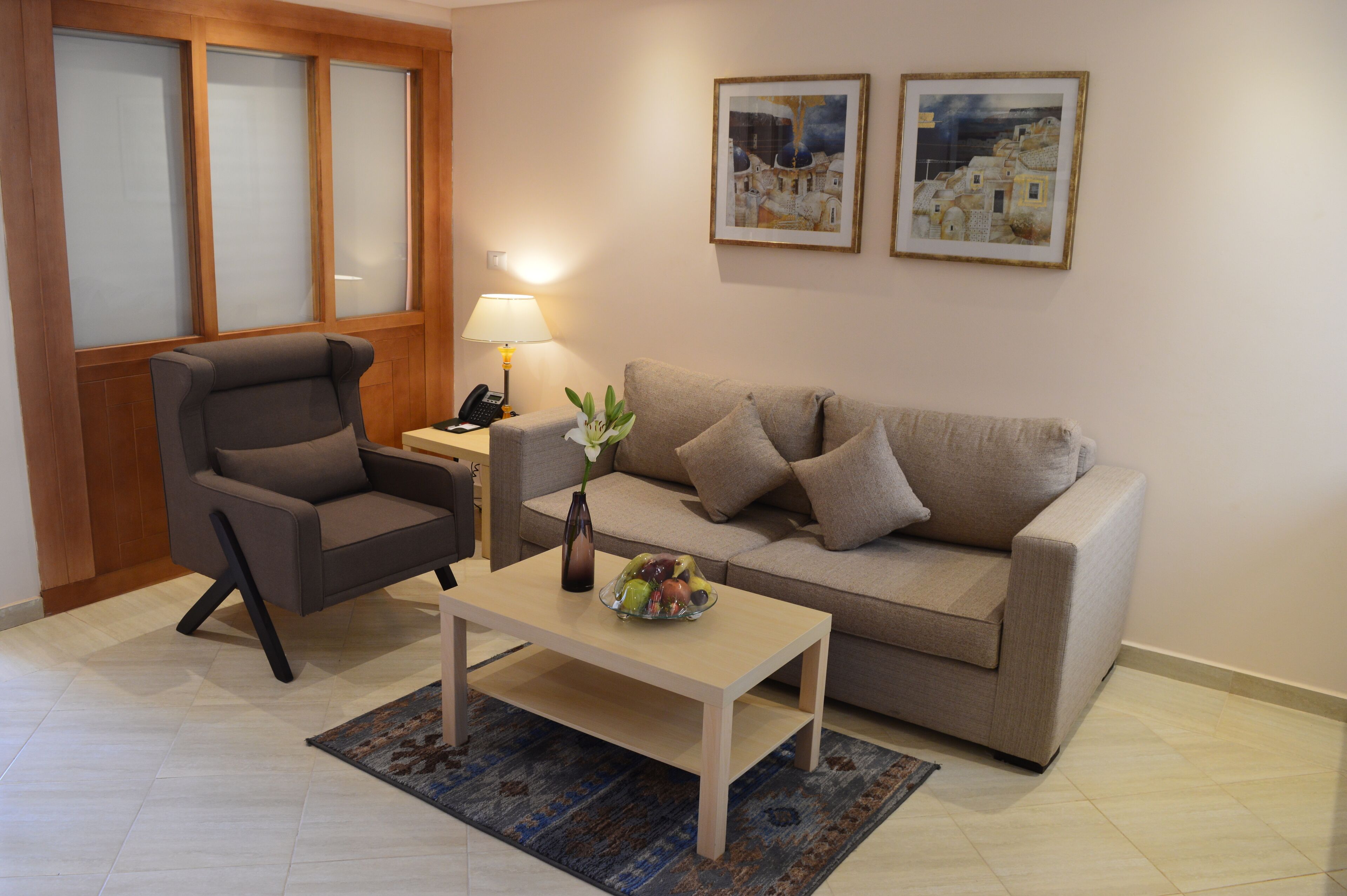 Una sala de estar con sofá, sillón, mesa de centro y lámpara.