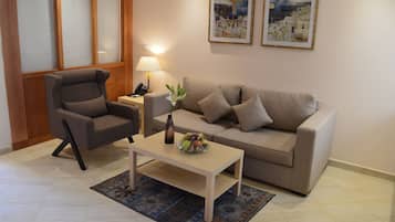 Una sala de estar con sofá, sillón, mesa de centro y lámpara.