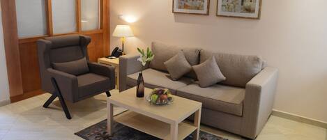 A living room with a sofa, armchair, coffee table, and a lamp.