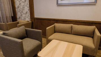 A room with a sofa, armchair, and a small table.