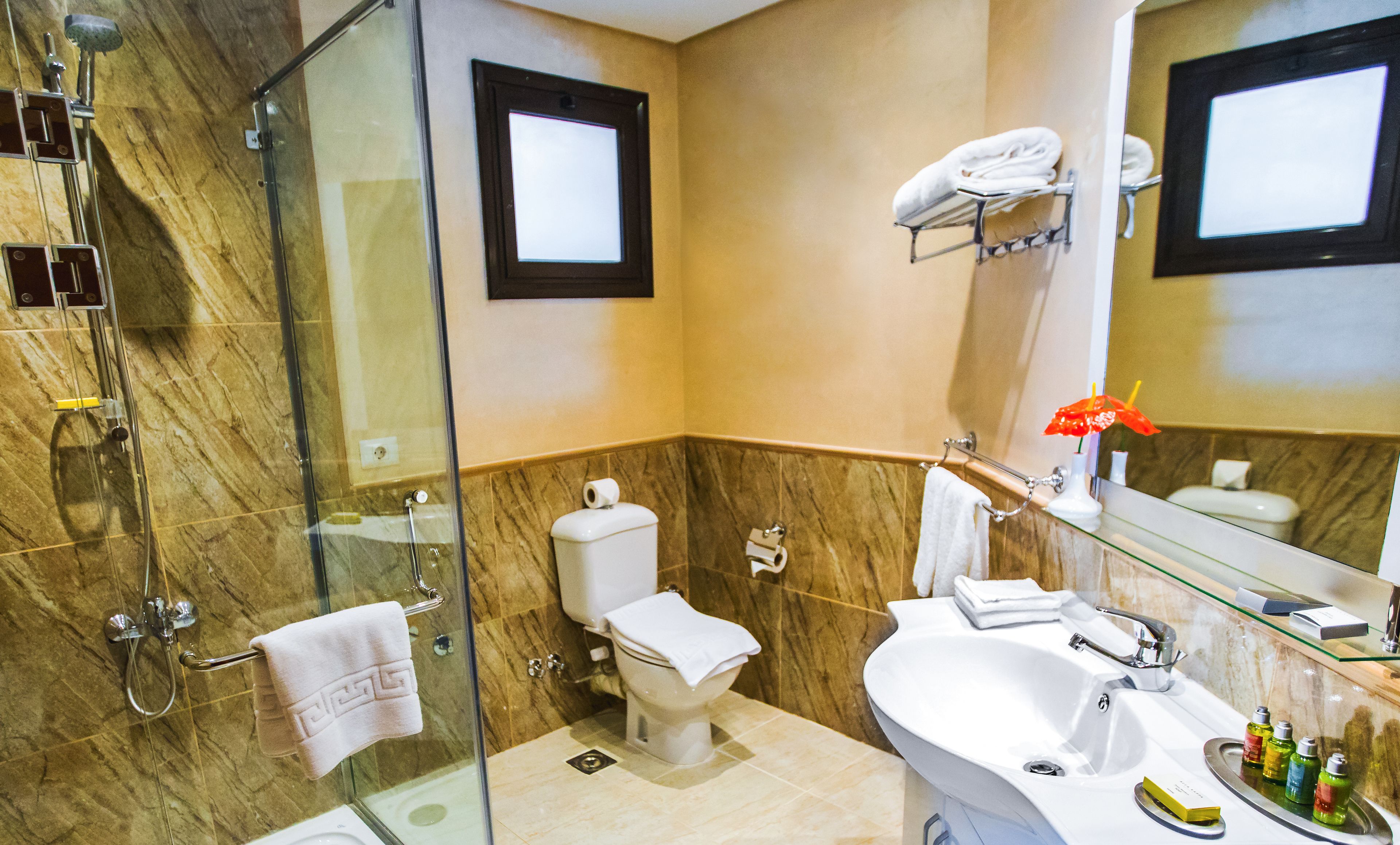 Une salle de bain moderne avec une douche à parois de verre, des toilettes, un lavabo et un meuble-lavabo avec des articles de toilette.