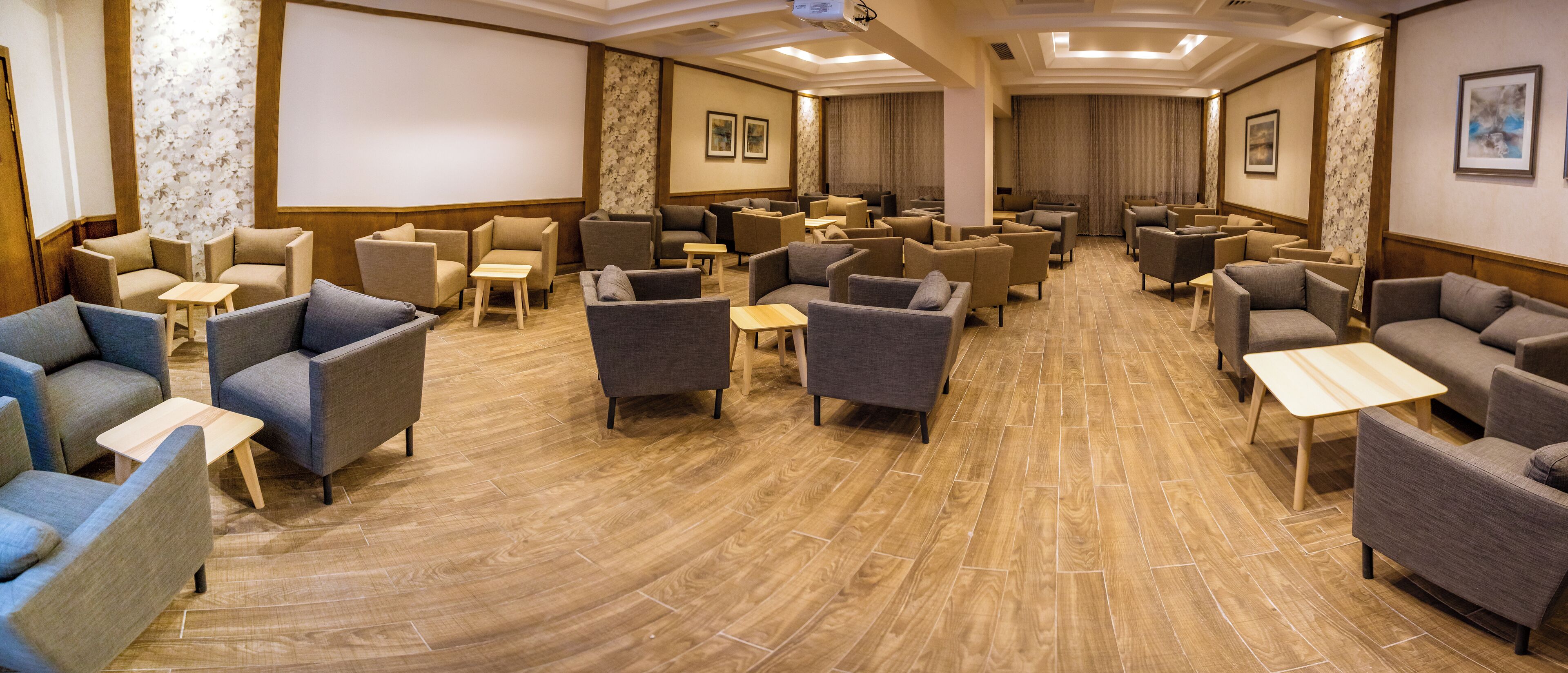 Um hall de hotel com várias áreas de estar, incluindo sofás e poltronas, dispostas em um espaço amplo.