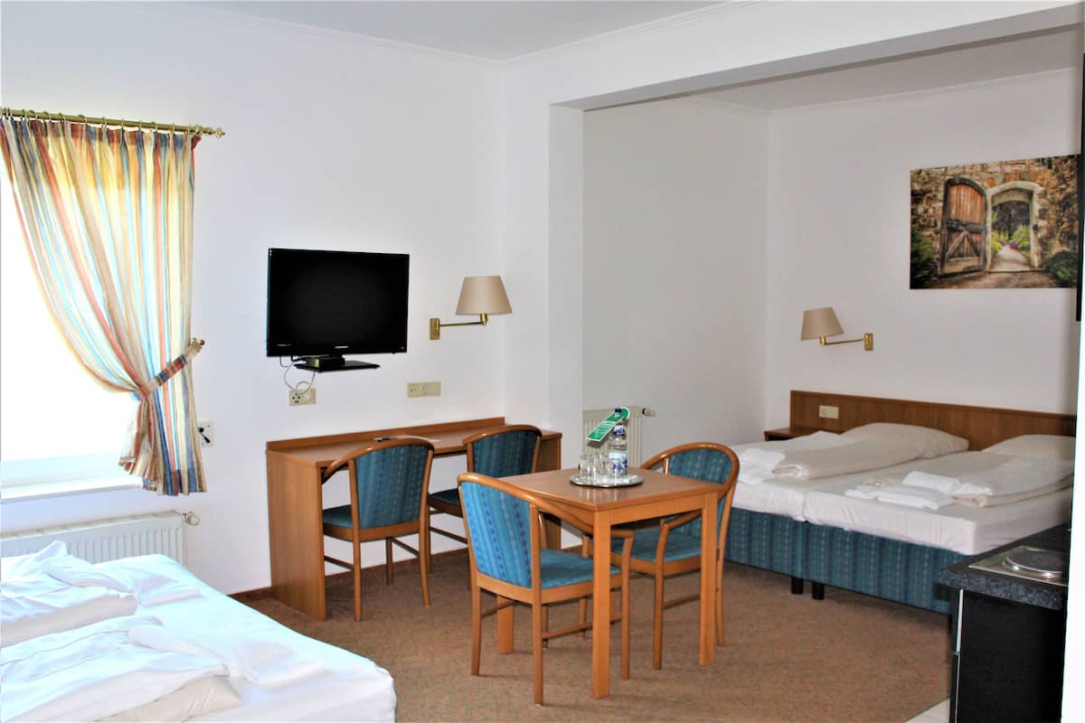 A hotel room with a bed, a desk with a chair, a television, two bedside tables, and a painting on the wall.