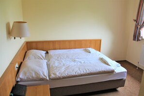 Cozy retreat with a comfortable bed, white linens, and a wall-mounted lamp.