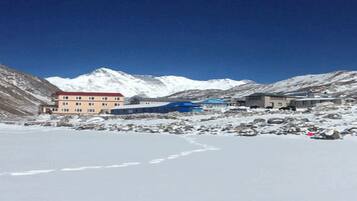 Un edificio con fachada roja y techo azul, rodeado de montañas nevadas.