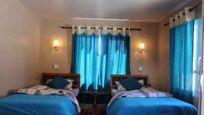 A double room with two beds, a small table, and curtains.