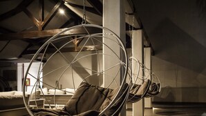 A modern interior with a hanging chair suspended from the ceiling, a sofa, and a coffee table. - Smy Civico Zero (Tarquinia)