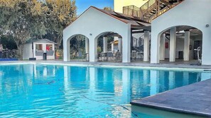 A swimming pool with a sun deck area, surrounded by white buildings with arched openings. - Smy Civico Zero (Tarquinia)