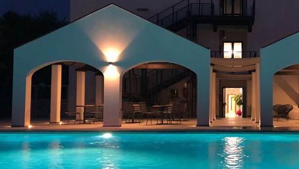 A modern poolside area with a clear view of the pool, a covered seating area, and a building entrance. - Smy Civico Zero (Tarquinia)