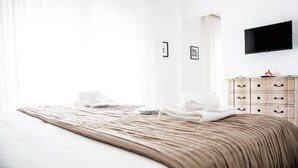 A hotel room with a large bed, a wooden dresser, and a flat-screen TV mounted on the wall. - Smy Civico Zero (Tarquinia)