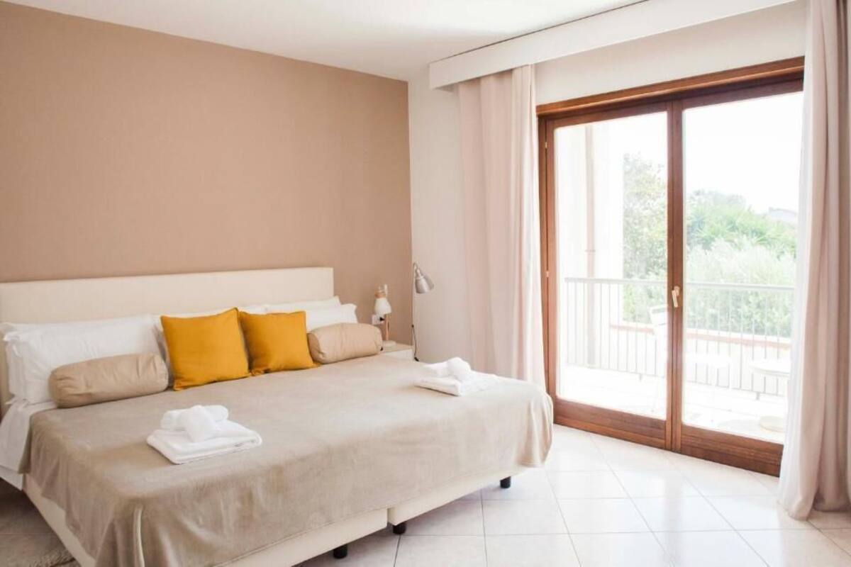 A hotel room with a large bed, a balcony with a view, and a sliding glass door.