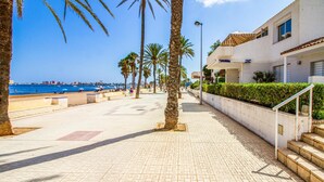 A coastal walkway with palm trees, a beach in the background, and a building with a white facade and blue windows. - 3 bedroom nice apartment in Cartagena (Cartagena)
