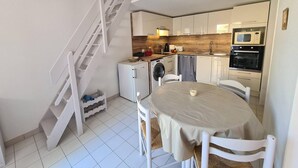 A compact kitchen with a dining area, a washing machine, and a microwave.