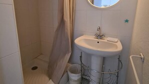A bathroom with a shower, a sink, and a mirror.