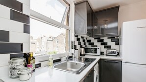 A modern kitchen with a large window, stainless steel appliances, and a view of the city. - WelcomeStay Clapham Junction 2 bedroom Apartment (London)