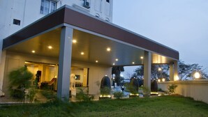 Um edifício moderno com área externa coberta, colunas e entrada bem iluminada.