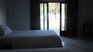 A hotel room with a bed, curtains, and a view of a garden through a sliding door.