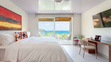 Un dormitorio con cama, escritorio, silla y un ventanal con vistas.
