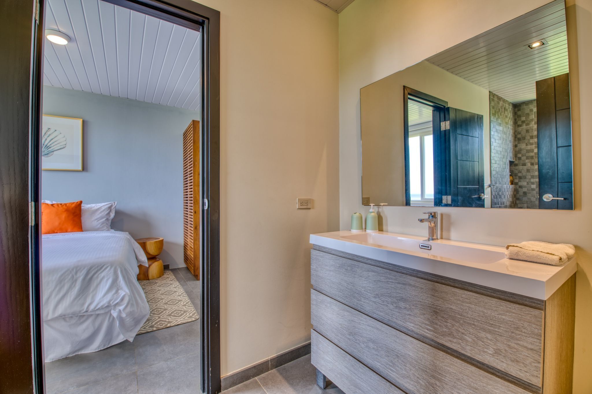 Un baño moderno con un espejo grande, un lavabo blanco y un mueble de tocador de madera.