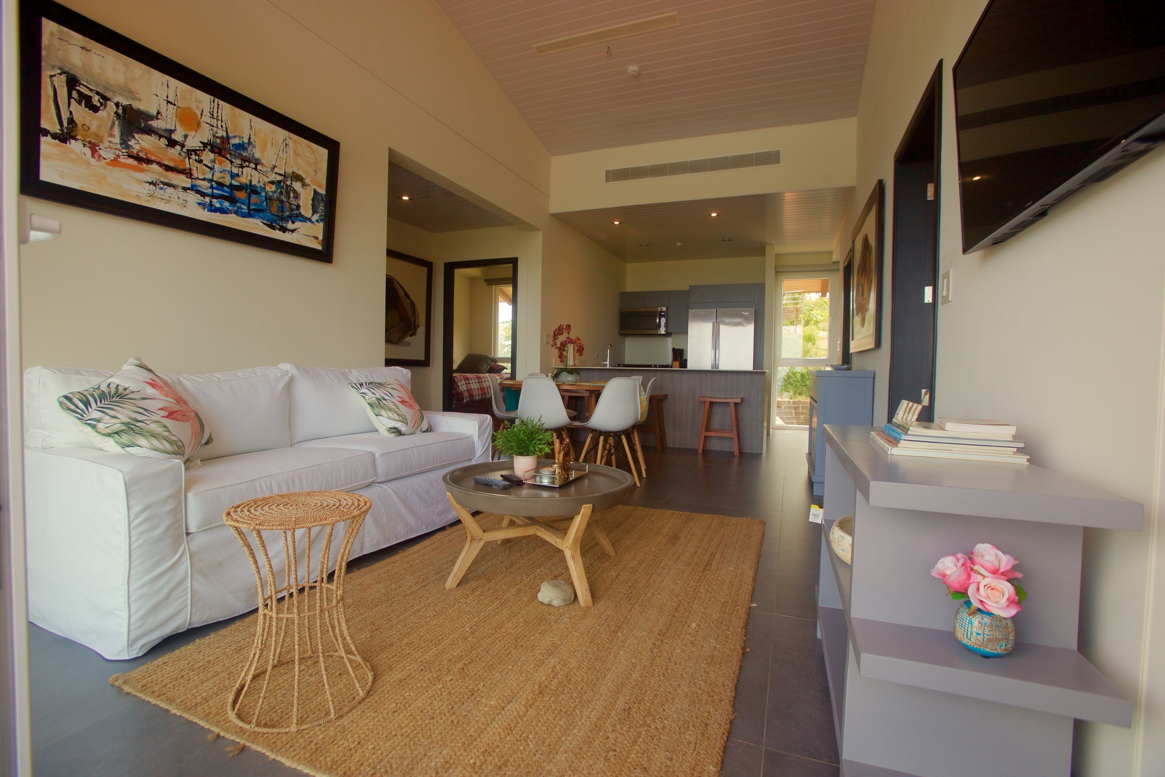 A modern living room with a white sofa, a round coffee table, and a kitchen in the background.