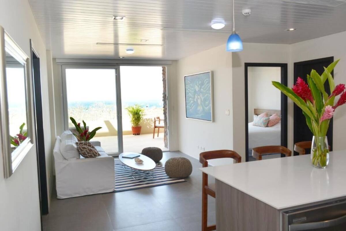 Een moderne woonkamer met een bank, een eettafel en uitzicht op de omgeving.