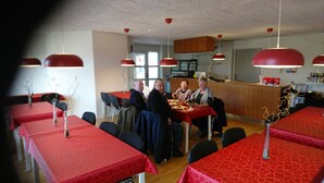 A restaurant with red tablecloths and black chairs. There are hanging red lamps above the tables. - Restaurant Vadehavet Mandø (Ribe)