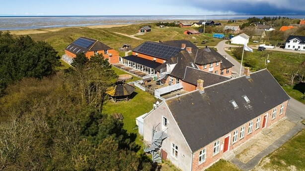 A coastal residential area with houses, some with solar panels, and a beach in the background. - Restaurant Vadehavet Mandø (Ribe)