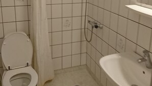A small, tiled bathroom with a toilet, shower, and sink. - Restaurant Vadehavet Mandø (Ribe)