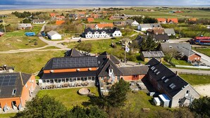 A coastal village with traditional houses, a large building with solar panels, and a view of the sea. - Restaurant Vadehavet Mandø (Ribe)