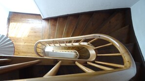 Een houten wenteltrap met een leuning en een centrale pilaar.
