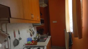 A kitchen with orange cabinets, a gas stove, and a sink. - Holiday apartment in a nice area (Cserkeszőlő)