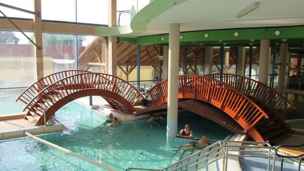 An indoor swimming pool with a wooden bridge and clear water. - Holiday apartment in a nice area (Cserkeszőlő)