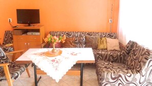 A living room with a sofa, a table with a lace tablecloth, a television on a stand, and a painting on the wall. - Holiday apartment in a nice area (Cserkeszőlő)