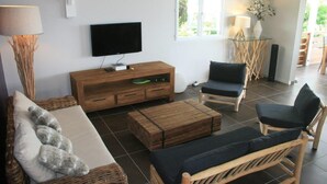 Una sala de estar moderna con televisor de pantalla plana, muebles de madera y una mesa de vidrio.