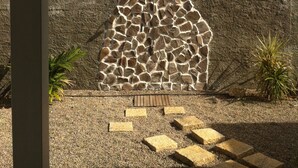 Un muro de piedra con un diseño original, cielo despejado y una montaña distante.