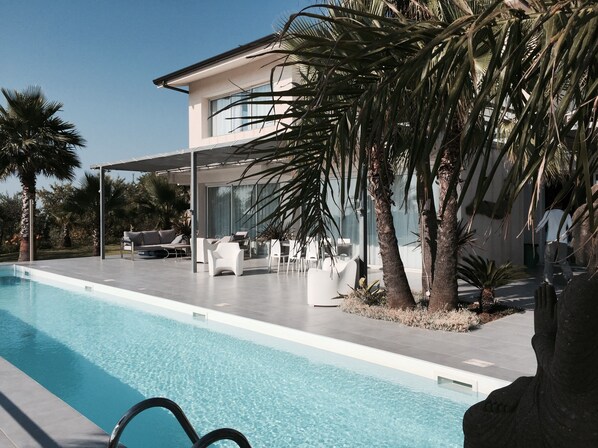 A modern poolside area with a clear pool, white outdoor furniture, and palm trees. - Villa Mozaic ...... wonderful setting with panoramic views, pool 16mX3 (Agrigento)