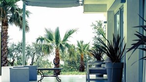 En overdækket patio med moderne møbler, palmer og plantekasser.