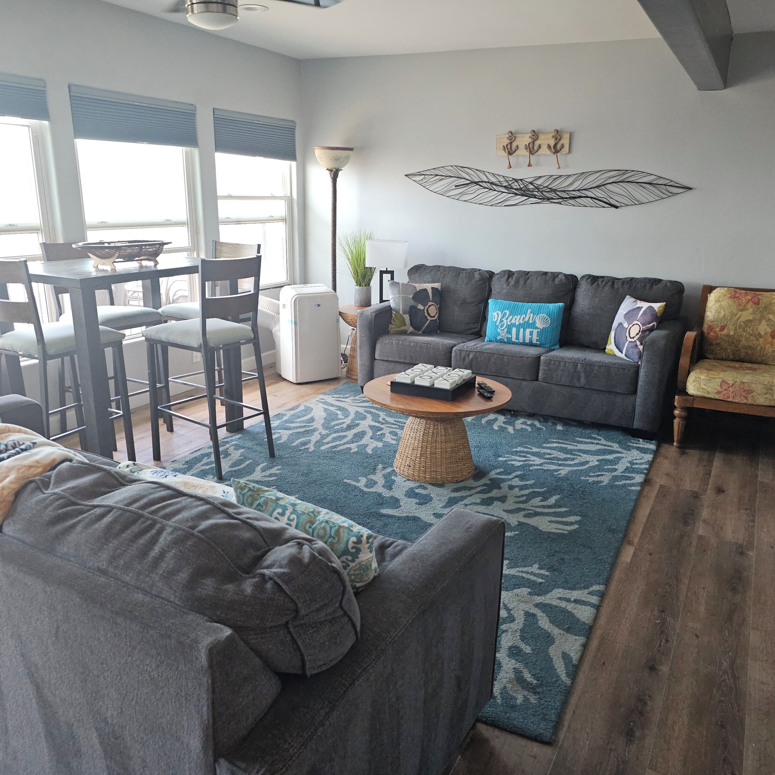 Ein Wohnzimmer mit grauem Sofa, einem Couchtisch und einem Essbereich mit Stühlen und Tisch.