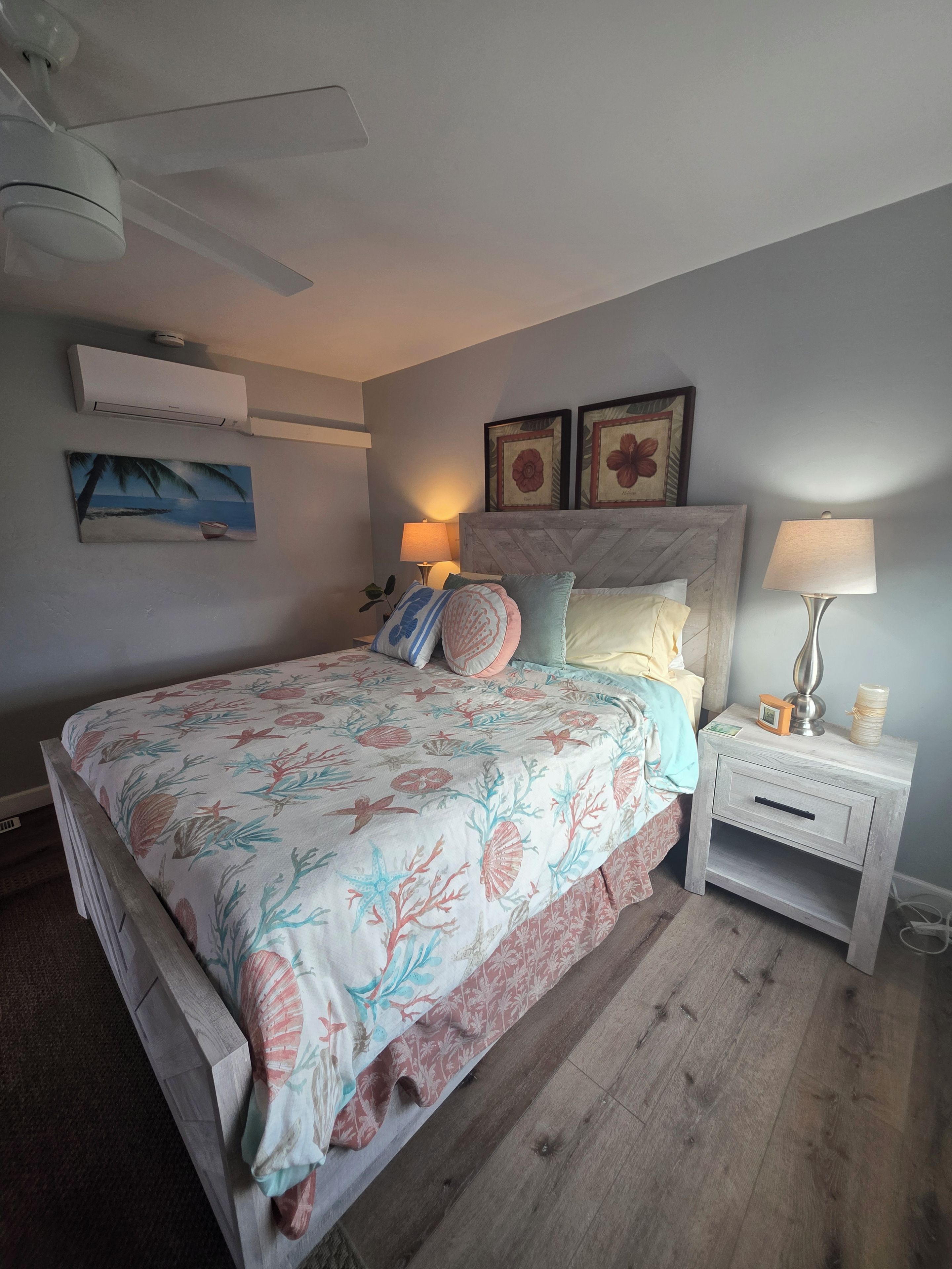 Un dormitorio con cama, mesita de noche, decoración en la pared y equipo de aire acondicionado.